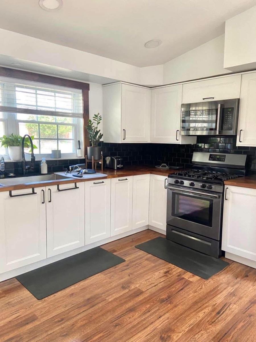 White kitchen with butcher block counters and a black backsplash